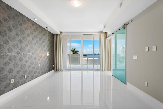 tiled spare room with expansive windows and a water view