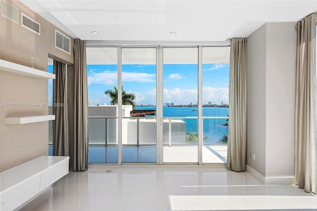 interior space featuring expansive windows, light tile patterned flooring, a water view, and a wealth of natural light