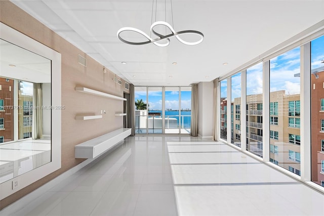 hallway featuring plenty of natural light, expansive windows, a chandelier, and light tile patterned flooring