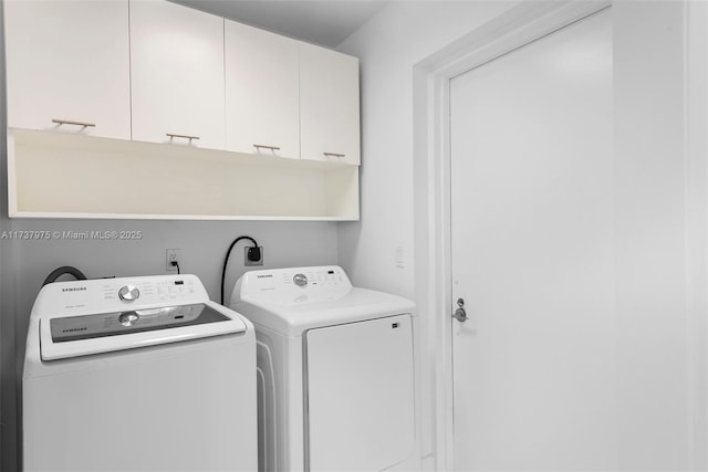 clothes washing area with cabinets and washer and dryer