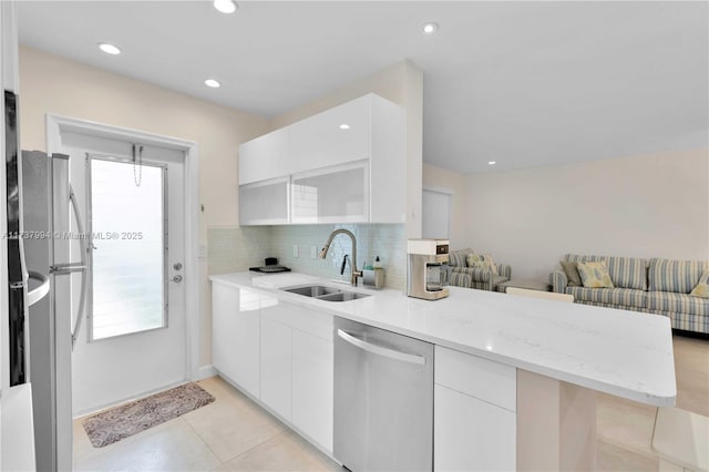 kitchen featuring sink, appliances with stainless steel finishes, white cabinets, decorative backsplash, and kitchen peninsula