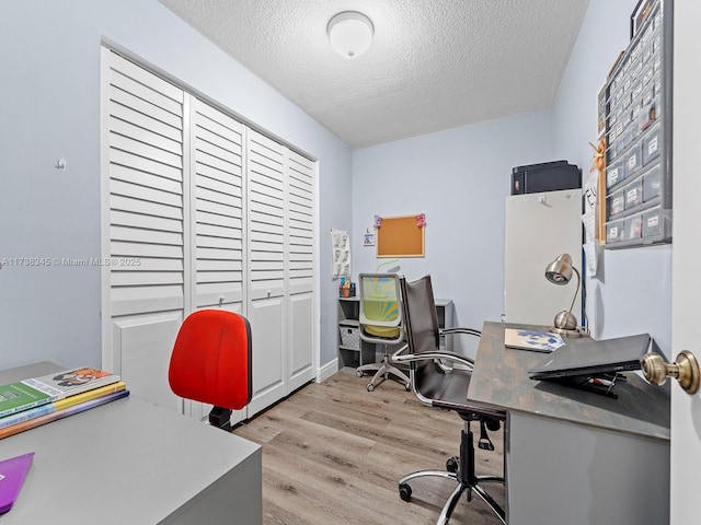 home office with light hardwood / wood-style floors and a textured ceiling