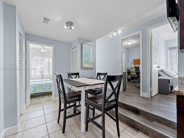 dining room with a textured ceiling and light hardwood / wood-style flooring