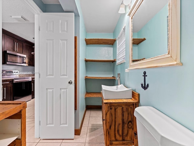 bathroom featuring tile patterned flooring, vanity, and toilet