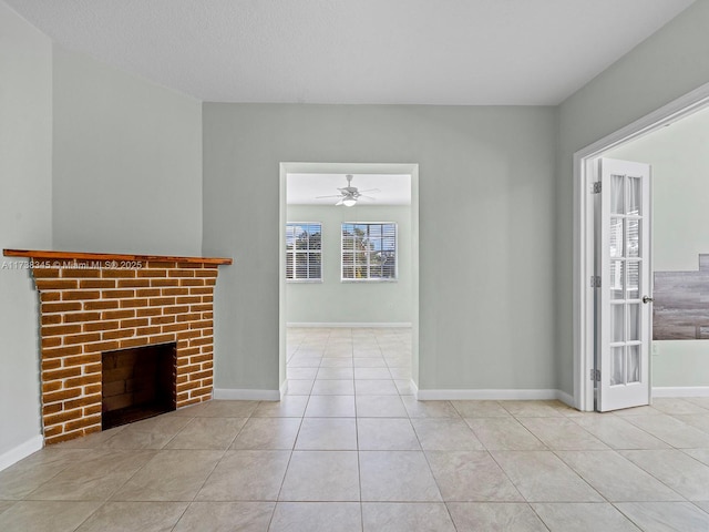 unfurnished living room with light tile patterned flooring, ceiling fan, and a brick fireplace