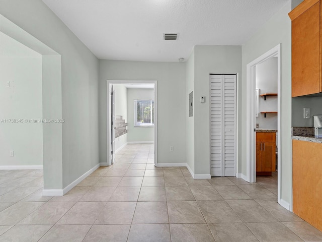 hallway with light tile patterned flooring and a textured ceiling