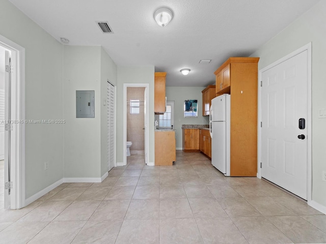 kitchen featuring light tile patterned floors, electric panel, and white refrigerator