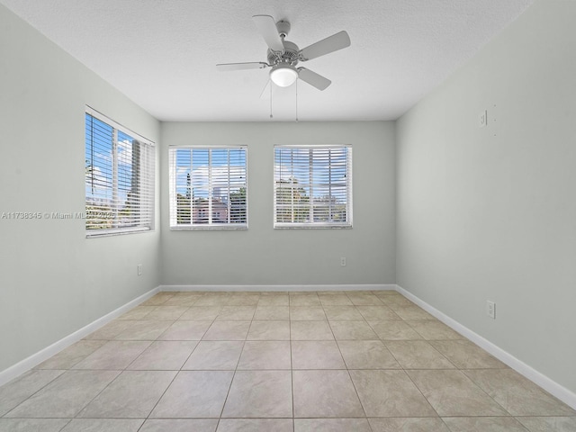 tiled spare room featuring ceiling fan, a healthy amount of sunlight, and a textured ceiling