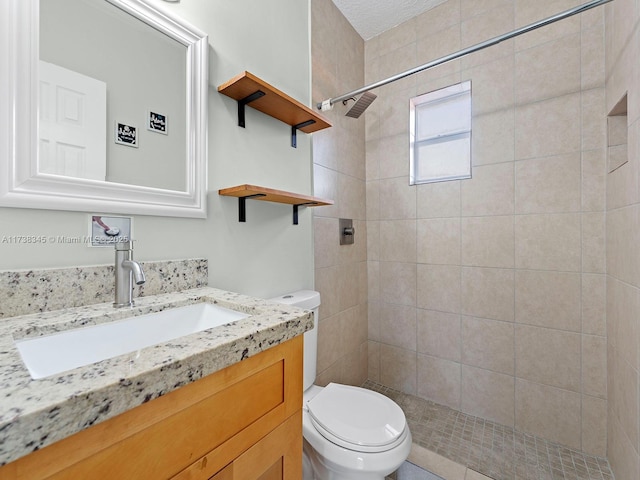 bathroom with vanity, tiled shower, and toilet