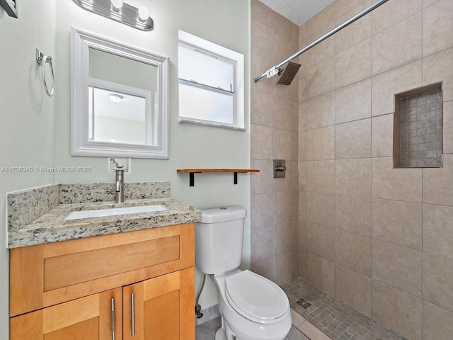 bathroom featuring vanity, toilet, and a tile shower