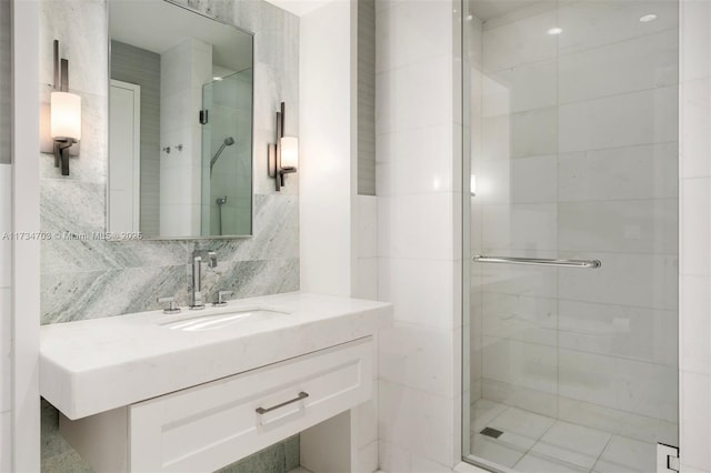 bathroom with vanity, backsplash, a shower with door, and tile walls