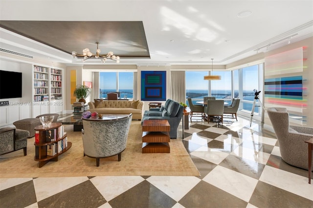 living room with a water view, a tray ceiling, a chandelier, and built in shelves