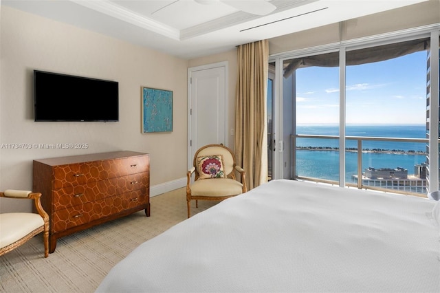 carpeted bedroom with a water view, a tray ceiling, crown molding, and access to outside