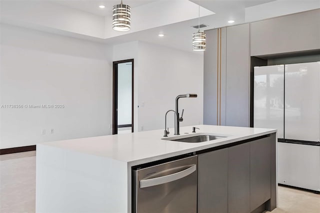 kitchen featuring a center island with sink, dishwasher, light countertops, freestanding refrigerator, and a sink