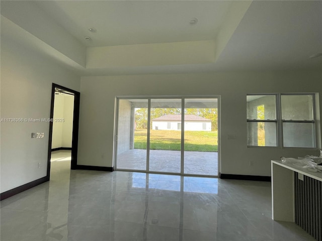 unfurnished room with a raised ceiling and baseboards