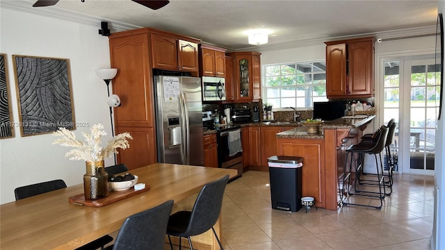 kitchen with a breakfast bar area, stainless steel appliances, crown molding, and a sink