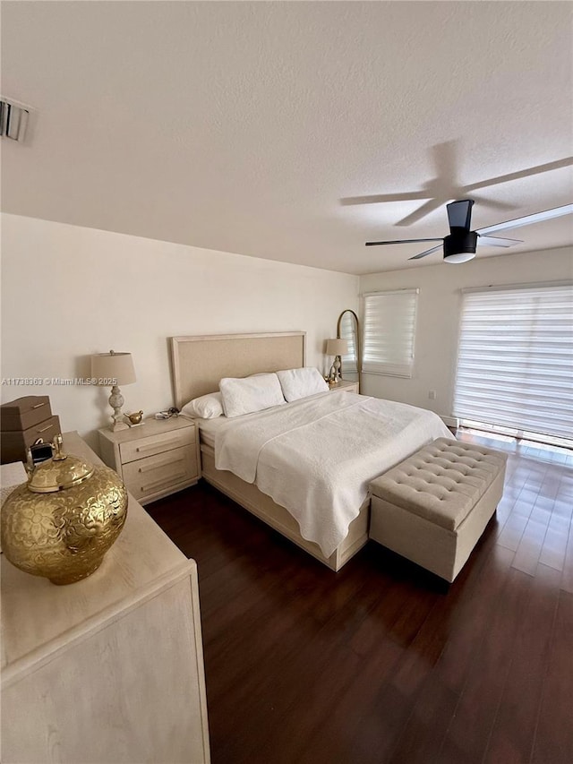 bedroom featuring ceiling fan, dark hardwood / wood-style flooring, and a textured ceiling