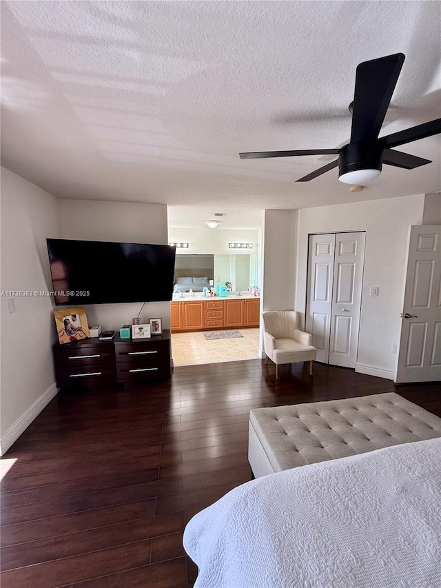 bedroom featuring ensuite bathroom, a textured ceiling, dark hardwood / wood-style floors, a closet, and ceiling fan