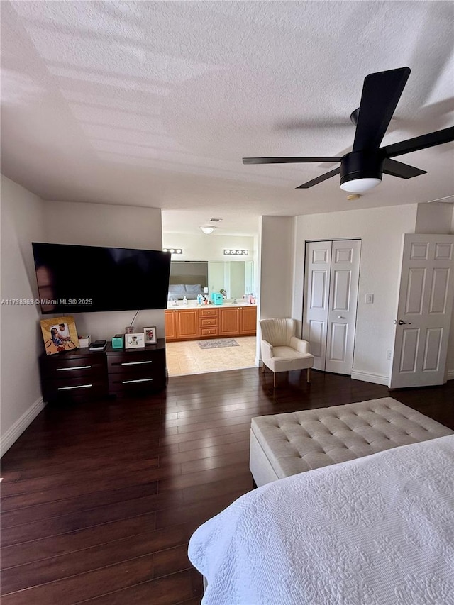 bedroom with ceiling fan, dark hardwood / wood-style floors, connected bathroom, and a textured ceiling