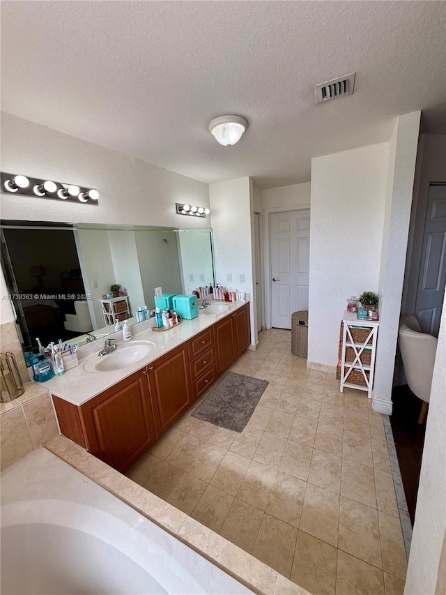 bathroom featuring vanity, tile patterned flooring, a textured ceiling, and a washtub