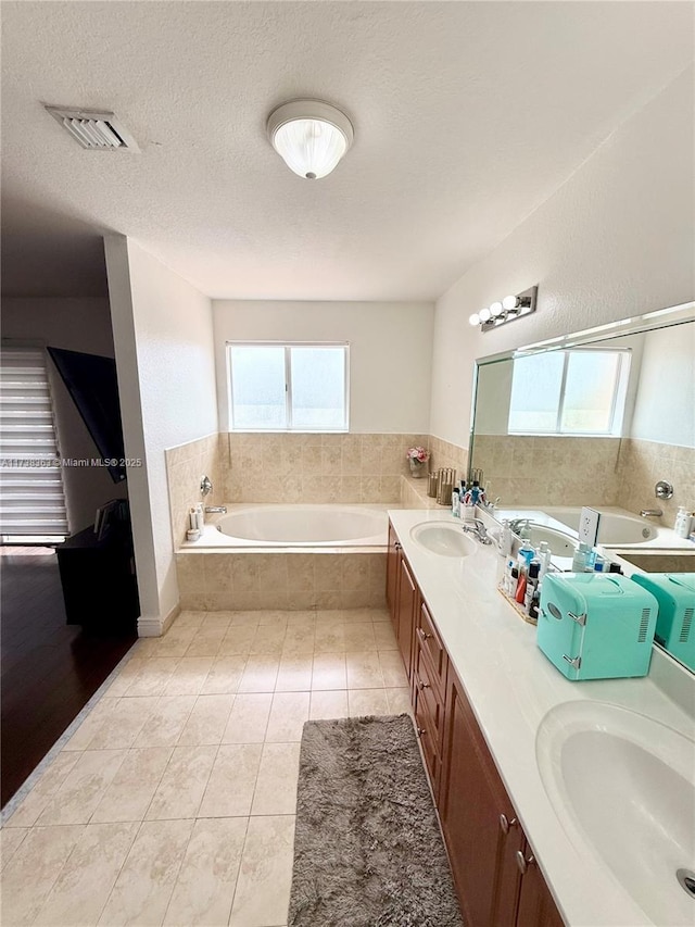 bathroom with vanity, tile patterned flooring, tiled bath, and a textured ceiling