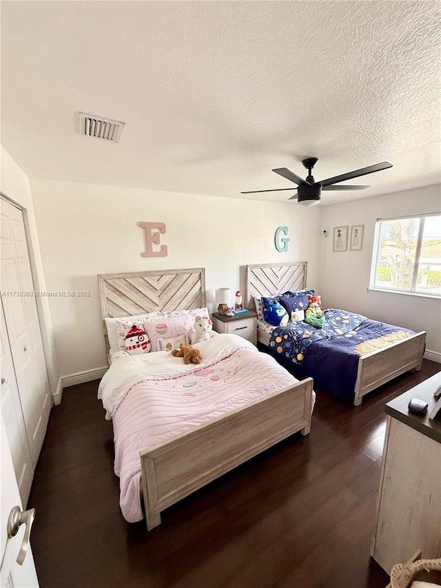 bedroom with dark hardwood / wood-style flooring, ceiling fan, and a textured ceiling