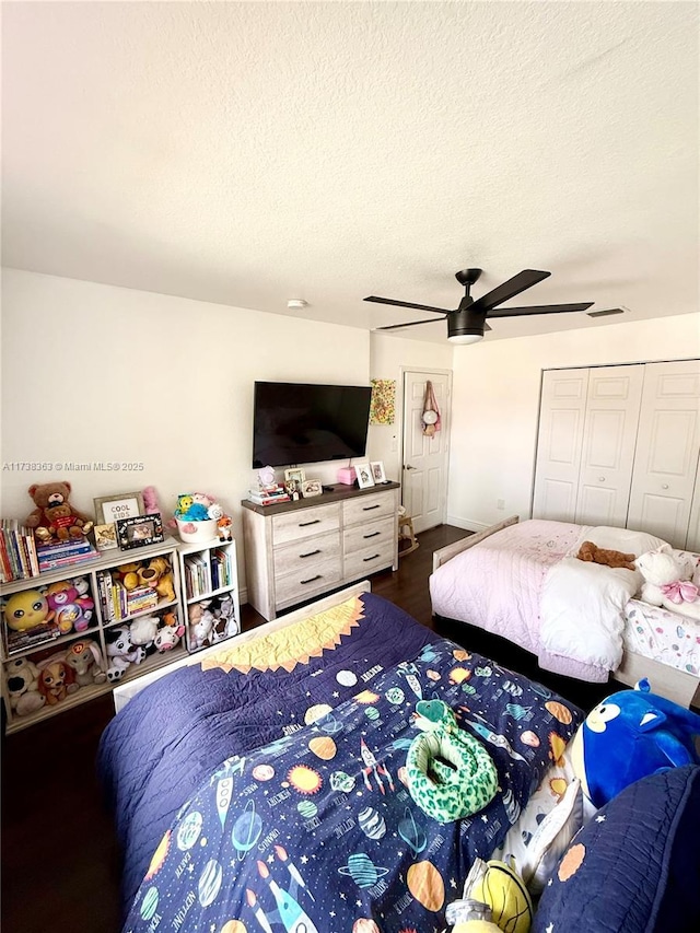 bedroom with ceiling fan, a closet, dark hardwood / wood-style floors, and a textured ceiling