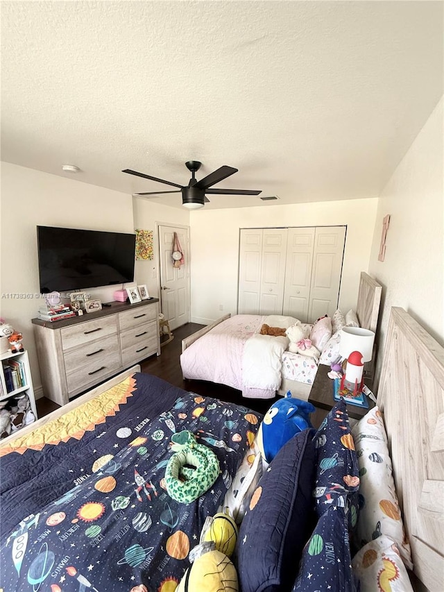 bedroom with ceiling fan, dark wood-type flooring, a closet, and a textured ceiling