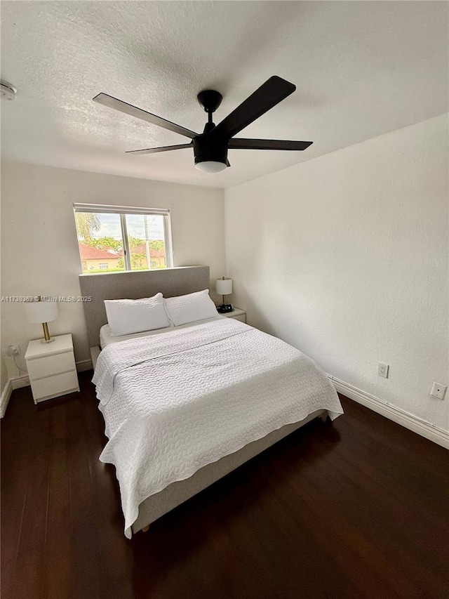 bedroom with dark hardwood / wood-style flooring, ceiling fan, and a textured ceiling