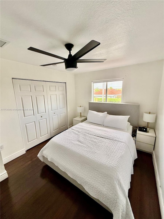 bedroom featuring ceiling fan, dark hardwood / wood-style flooring, a textured ceiling, and a closet