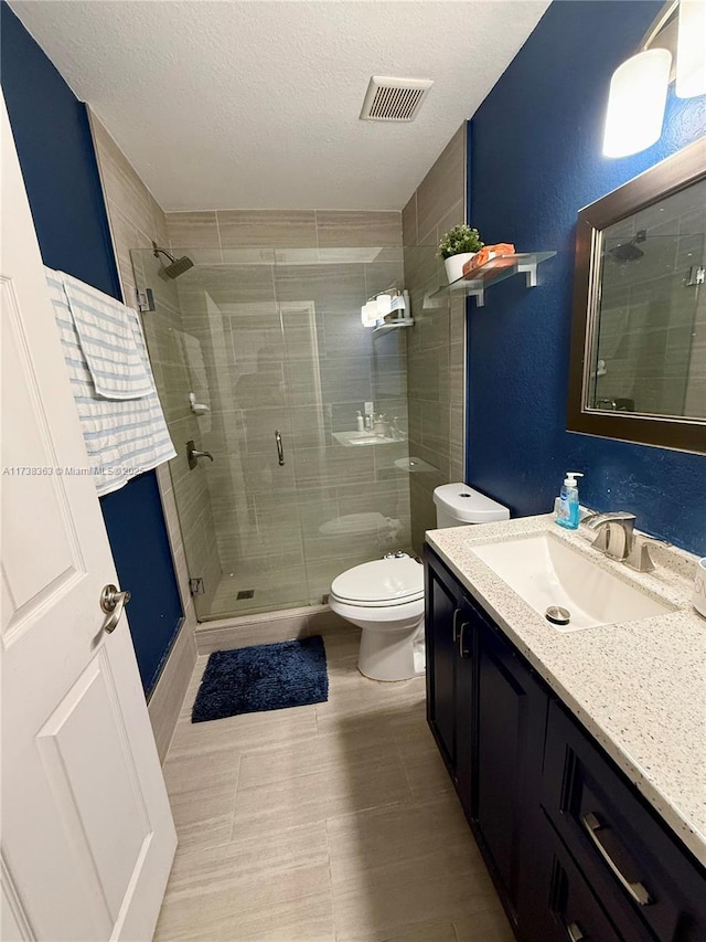 bathroom with vanity, a textured ceiling, a shower with shower door, and toilet