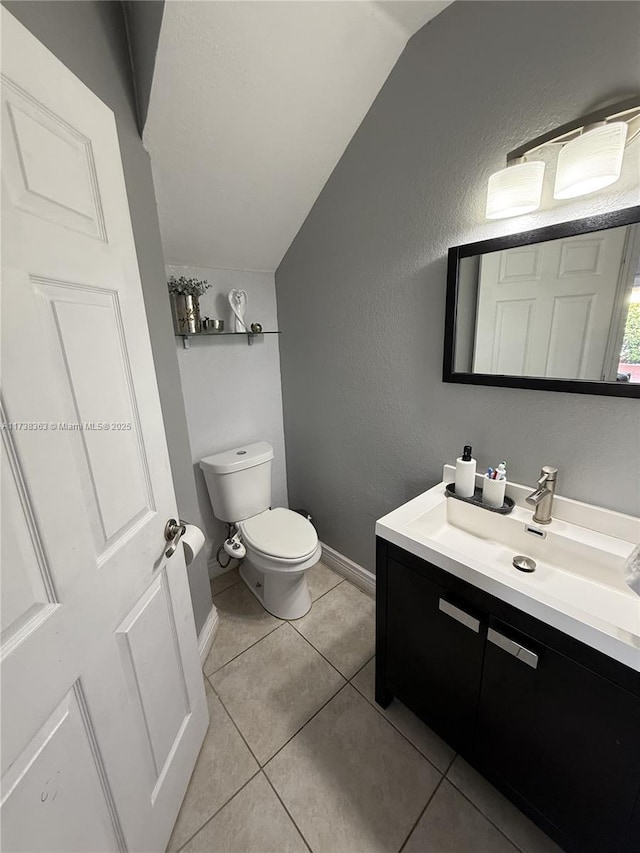 bathroom with vanity, lofted ceiling, tile patterned floors, and toilet