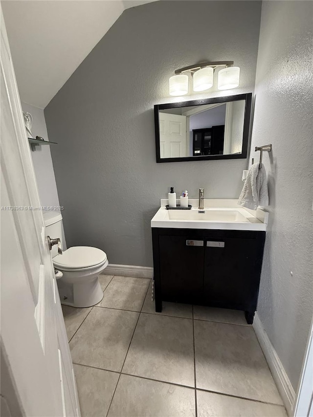 bathroom with tile patterned flooring, vanity, vaulted ceiling, and toilet