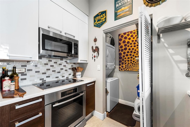 kitchen with stacked washer and clothes dryer, dark brown cabinets, appliances with stainless steel finishes, decorative backsplash, and white cabinets