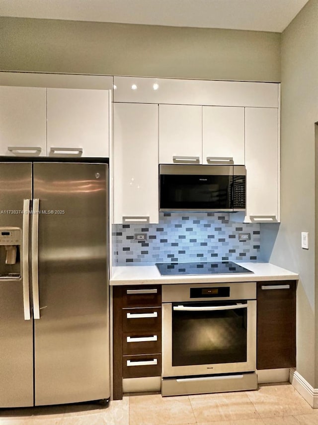 kitchen featuring stainless steel appliances, white cabinets, and decorative backsplash