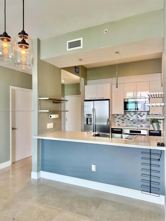 kitchen featuring stainless steel appliances, white cabinetry, tasteful backsplash, and pendant lighting