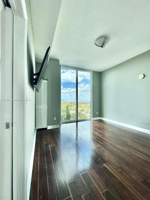 unfurnished room with dark hardwood / wood-style floors and expansive windows