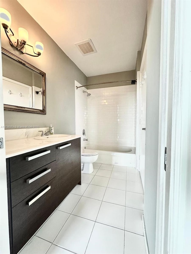 full bathroom with tile patterned flooring, tiled shower / bath, vanity, and toilet