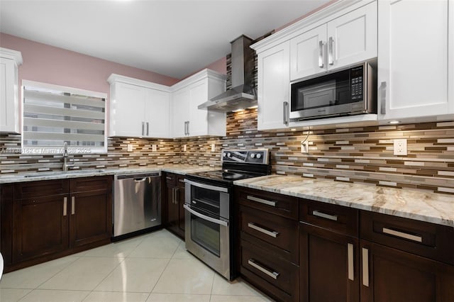 kitchen featuring wall chimney exhaust hood, white cabinetry, stainless steel appliances, and sink