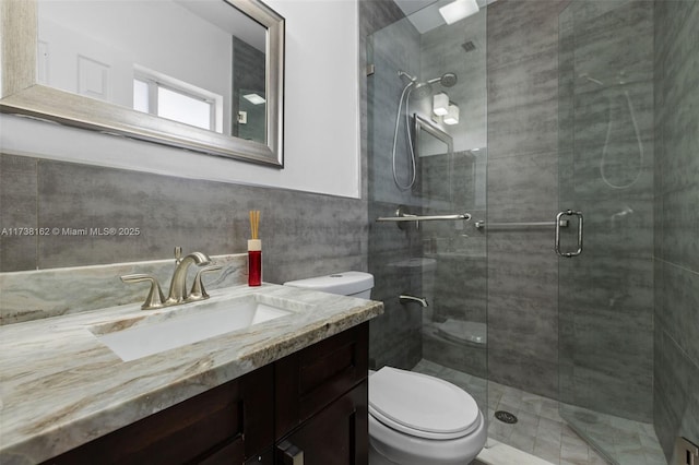 bathroom with toilet, tile walls, vanity, and walk in shower