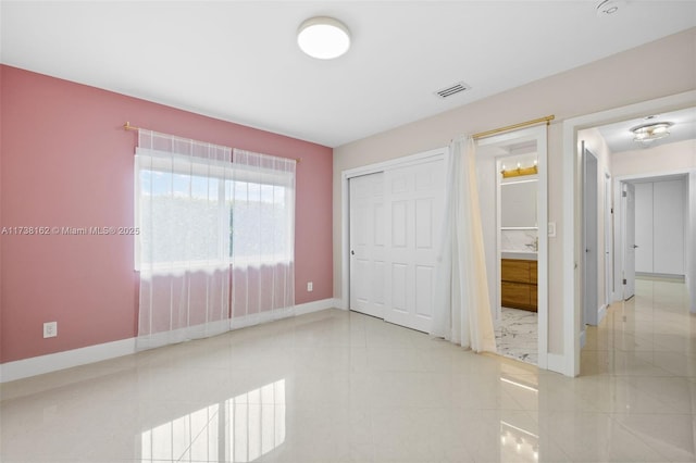 unfurnished bedroom with light tile patterned floors, ensuite bath, and a closet