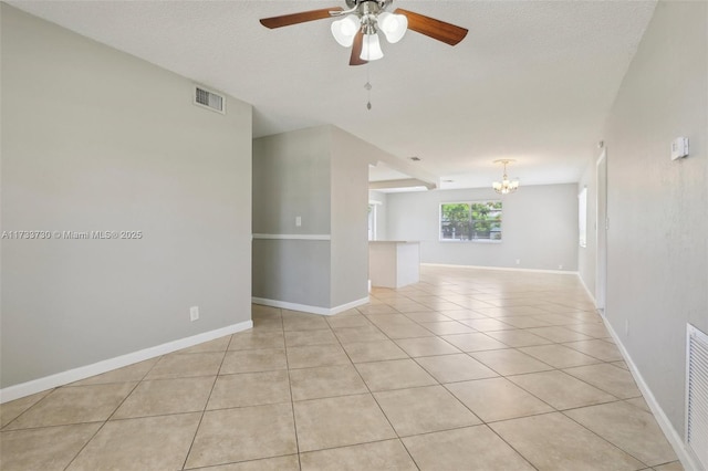 tiled empty room with ceiling fan with notable chandelier and a textured ceiling