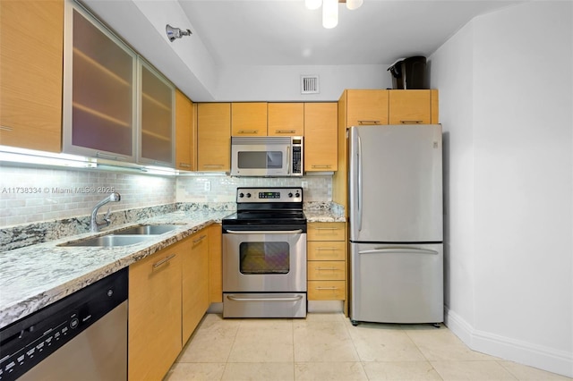 kitchen featuring appliances with stainless steel finishes, sink, backsplash, light stone counters, and light brown cabinets