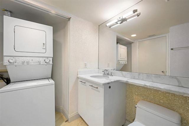 interior space with stacked washing maching and dryer, sink, and light tile patterned floors