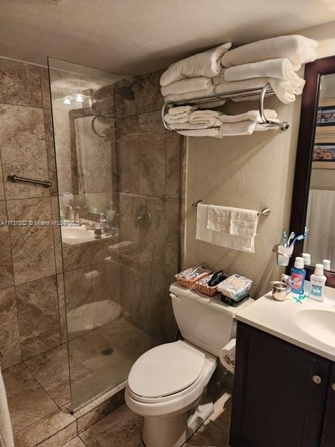 bathroom featuring vanity, toilet, a textured ceiling, and a tile shower