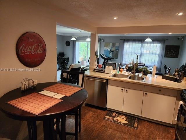 kitchen featuring sink, dark wood-type flooring, dishwasher, white cabinets, and decorative light fixtures