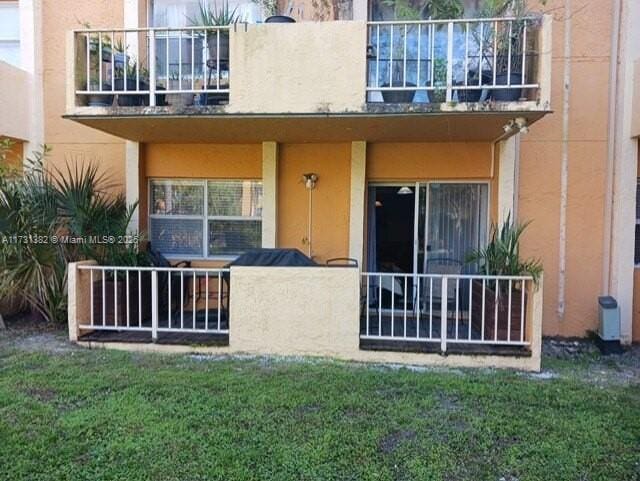 back of house with a lawn and a balcony