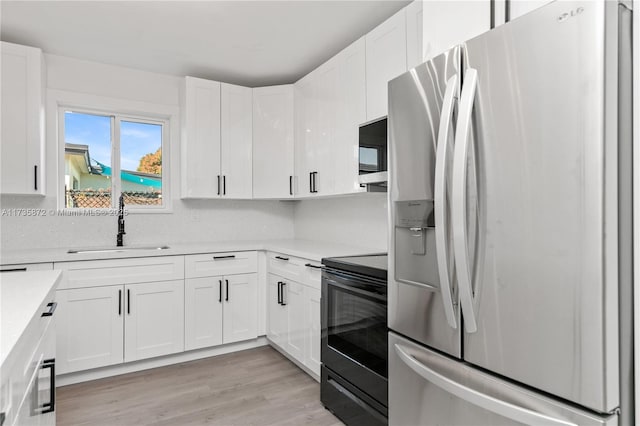 kitchen with white cabinetry, stainless steel refrigerator with ice dispenser, electric range oven, and sink