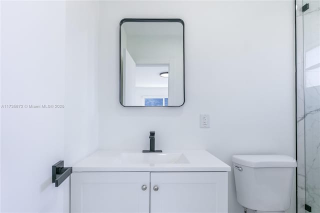 bathroom featuring vanity, walk in shower, and toilet