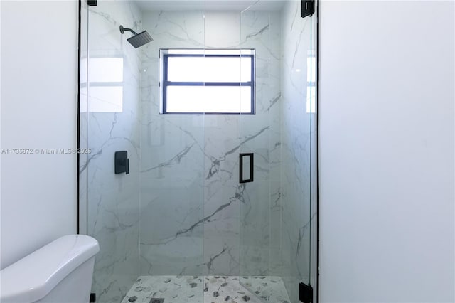 bathroom with a shower with door and toilet